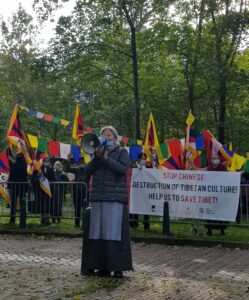 Tsering Jampa voor de Chinese ambassade in Den Haag, met Tibet-supporters en gebedsvlaggen op de achtergrond